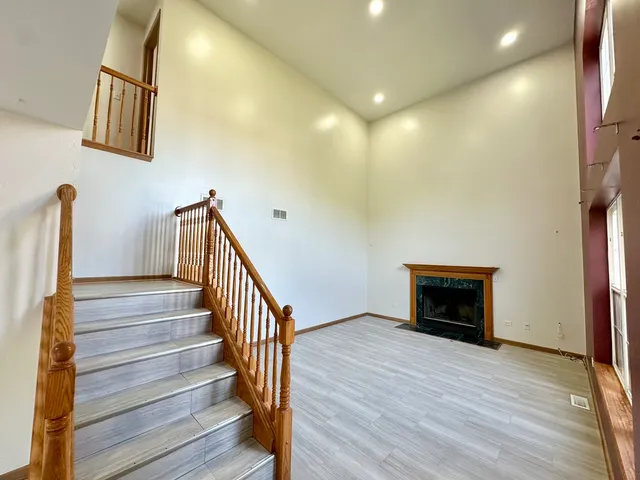 a view of an empty room with wooden floor and a fireplace