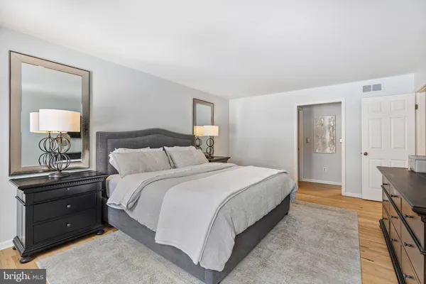 a bedroom with a bed and a lamp on dresser