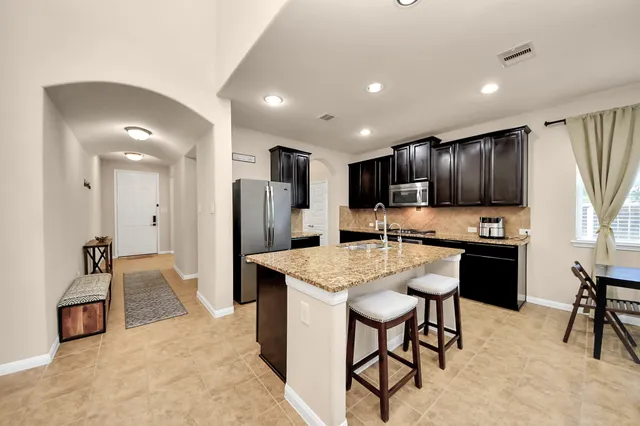 a kitchen with stainless steel appliances kitchen island granite countertop a refrigerator and a stove top oven