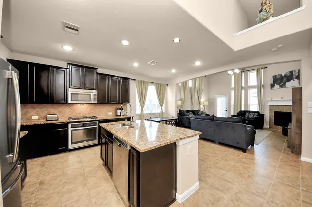 a large kitchen with kitchen island a stove a refrigerator a sink dishwasher a dining table and chairs with wooden floor