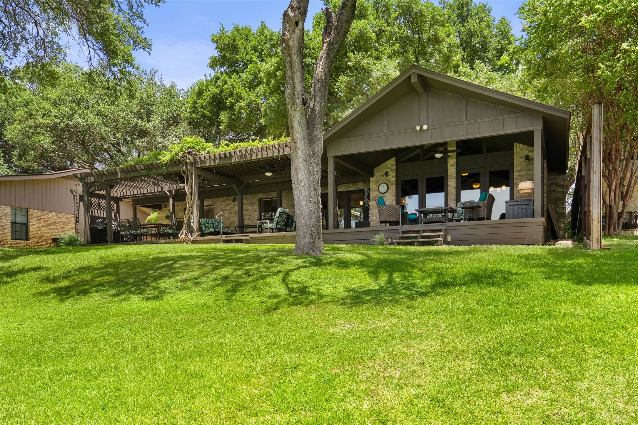 141 Perry Lane Kingsland, TX 78639 - Photo 3 of 40 A spacious backyard with mature trees and a covered deck offers a serene outdoor living space.