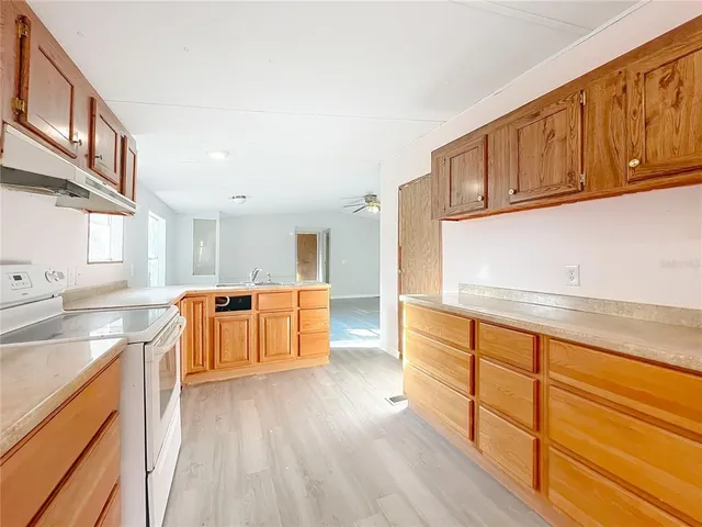 a kitchen with stainless steel appliances granite countertop a sink and wooden cabinets with wooden floors
