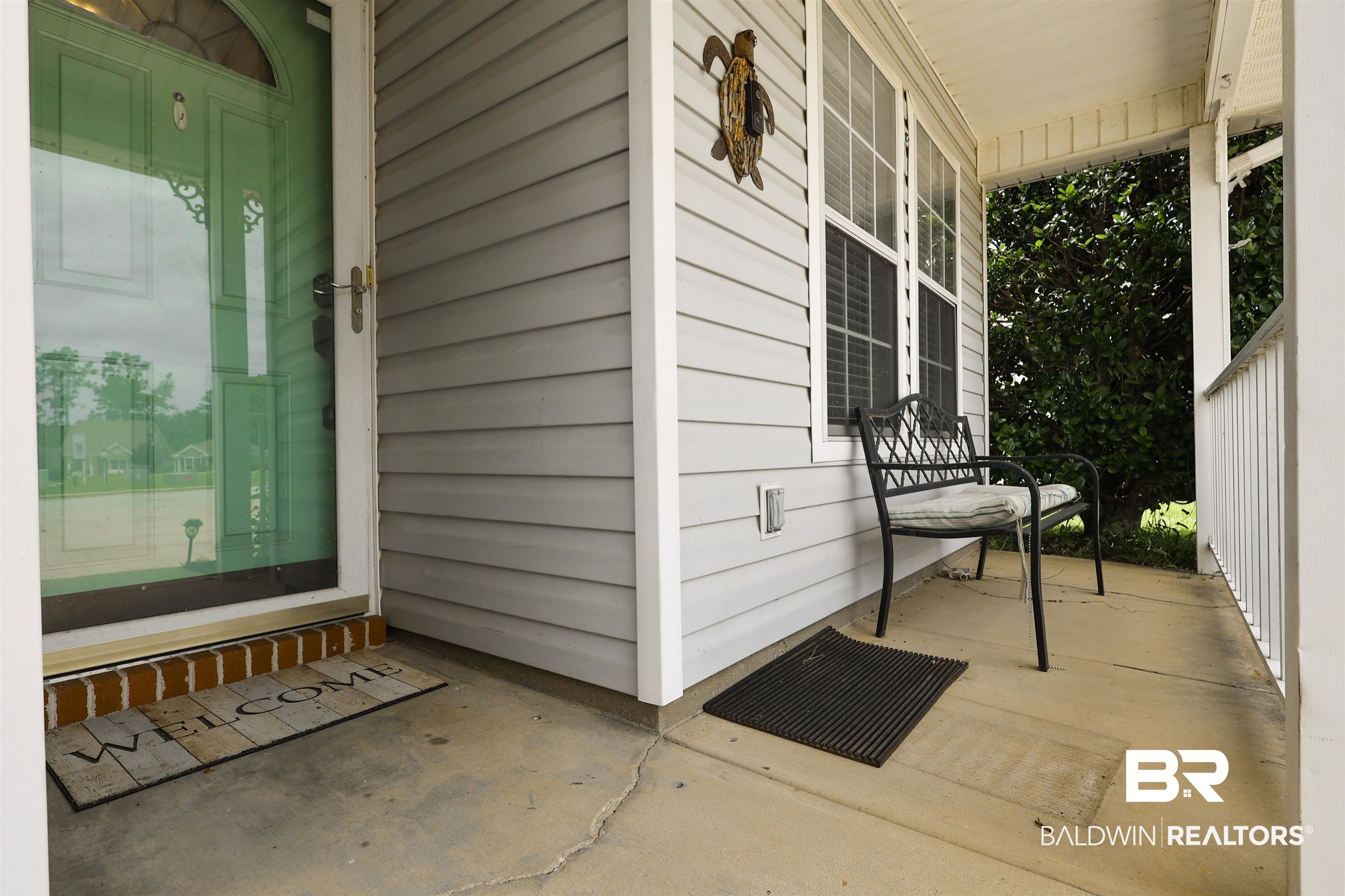 7790 Audubon Drive Foley, AL 36535 - Photo 6 of 39 Covered front porch featuring light gray siding, white trim, and a concrete floor
