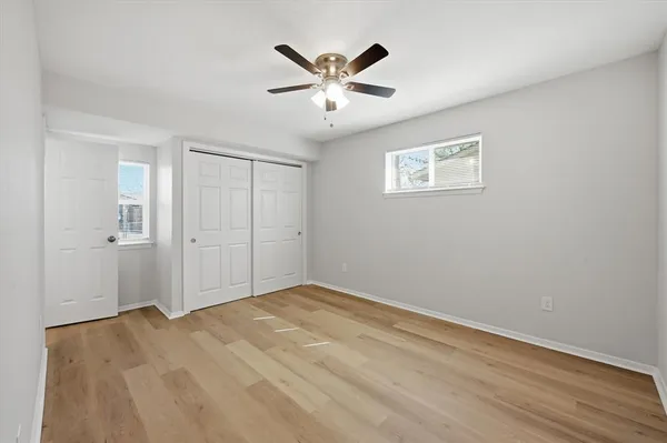 an empty room with wooden floor and ceiling fan