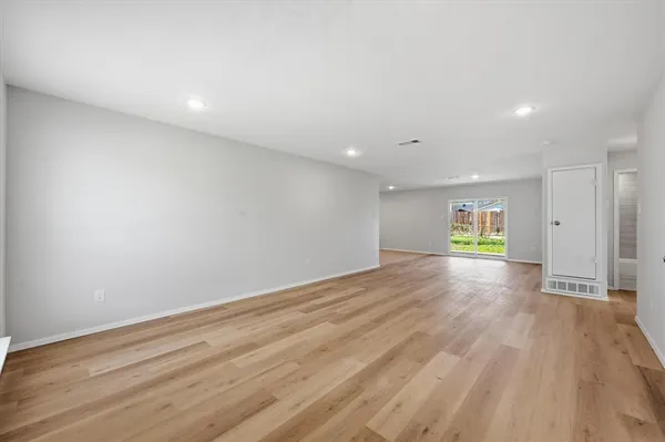 a view of empty room with wooden floor and window