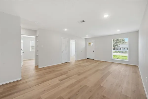 a view of an empty room with wooden floor and a window