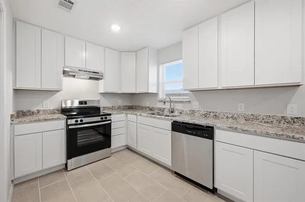 a kitchen with granite countertop white cabinets and stainless steel appliances