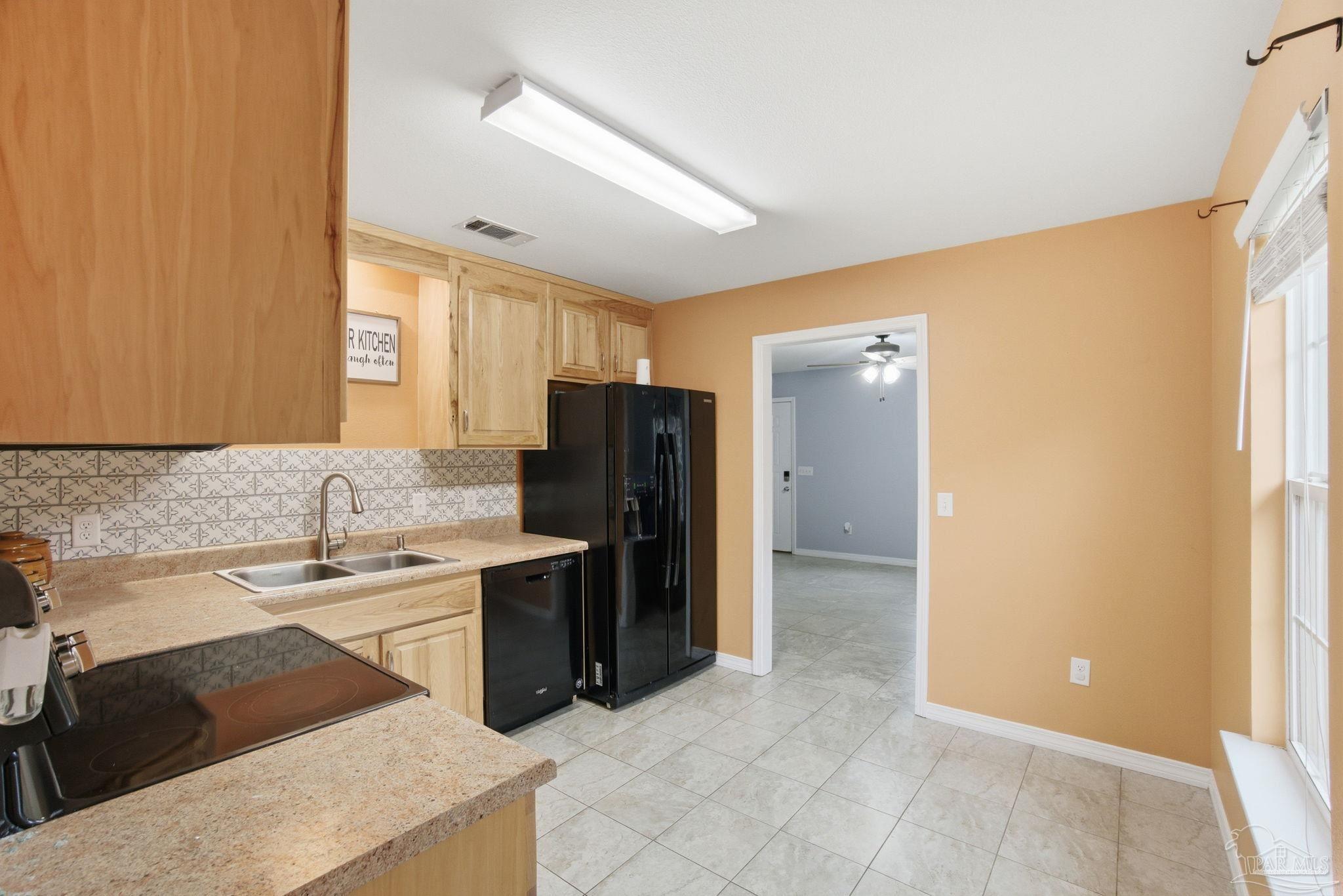 4393 Rice Road Milton, FL 32583 - Photo 14 of 52 a kitchen with a sink a refrigerator and cabinets