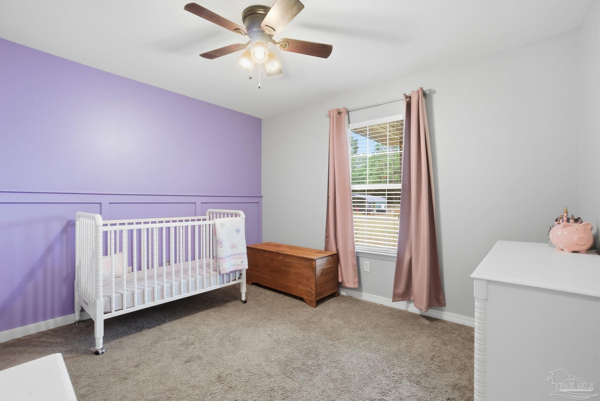 4393 Rice Road Milton, FL 32583 - Photo 19 of 52 a bedroom with a baby bed a chandelier and a dresser