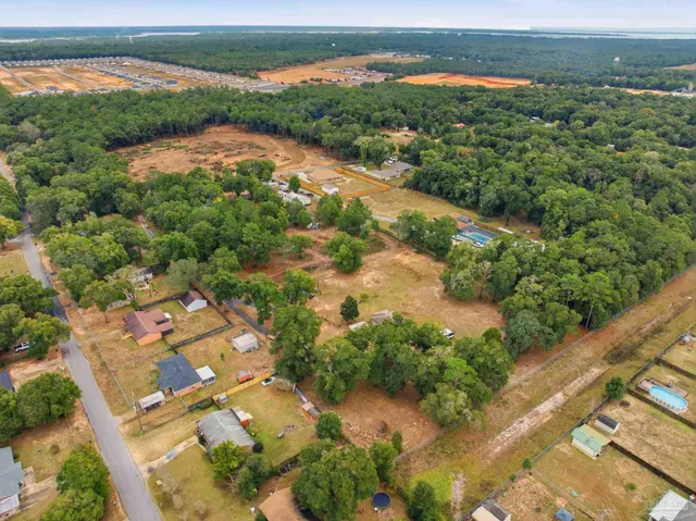 an aerial view of residential houses with outdoor space and trees