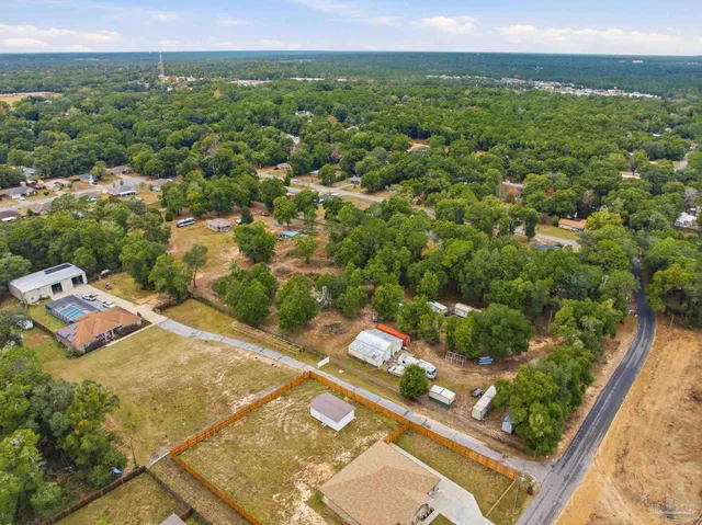 an aerial view of residential houses with outdoor space and trees