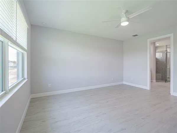 an empty room with windows and fan