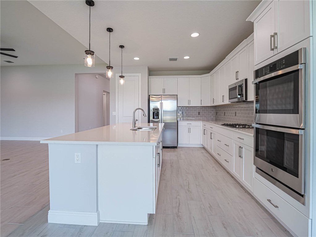 6422 High Pointe W Way Vero Beach, FL 32967 - Photo 6 of 33 a large kitchen with stainless steel appliances kitchen island granite countertop a stove a sink and a refrigerator