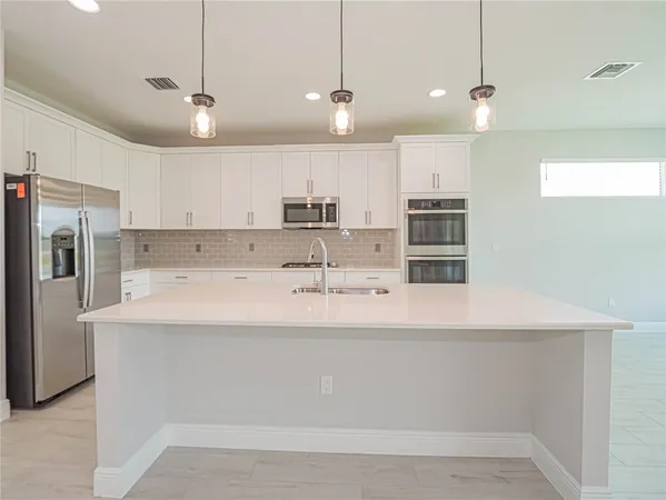 a view of a kitchen with kitchen island a sink stainless steel appliances and a counter top space