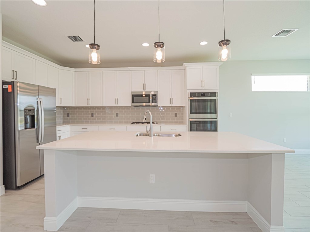 6422 High Pointe W Way Vero Beach, FL 32967 - Photo 7 of 33 a view of a kitchen with kitchen island a sink stainless steel appliances and a counter top space