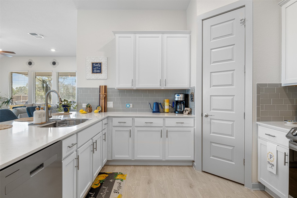 109 Rambling Rapids Drive Georgetown, TX 78628 - Photo 13 of 37 Kitchen with appliances with stainless steel finishes, white cabinets, light wood-type flooring, light stone counters, and recessed lighting