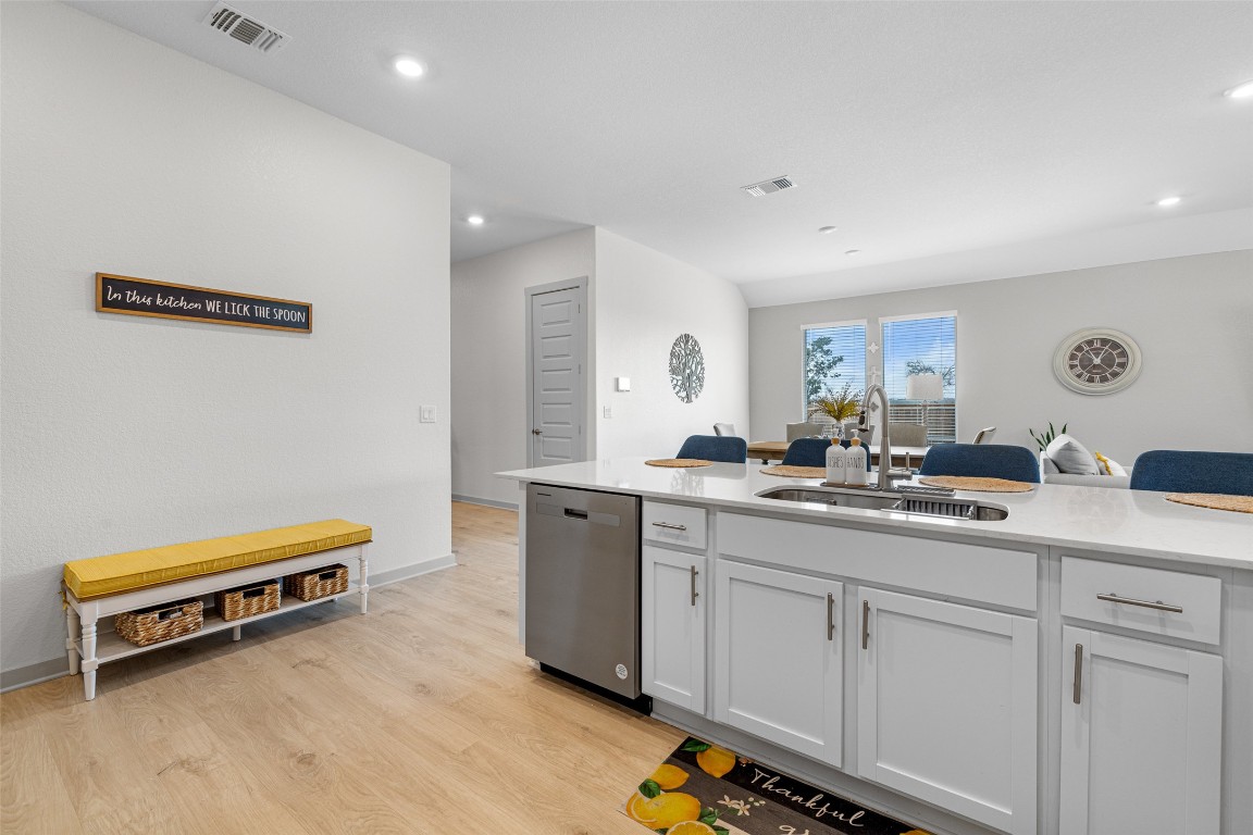 109 Rambling Rapids Drive Georgetown, TX 78628 - Photo 14 of 37 Kitchen with white cabinets, light wood finished floors, light stone countertops, dishwasher, and recessed lighting