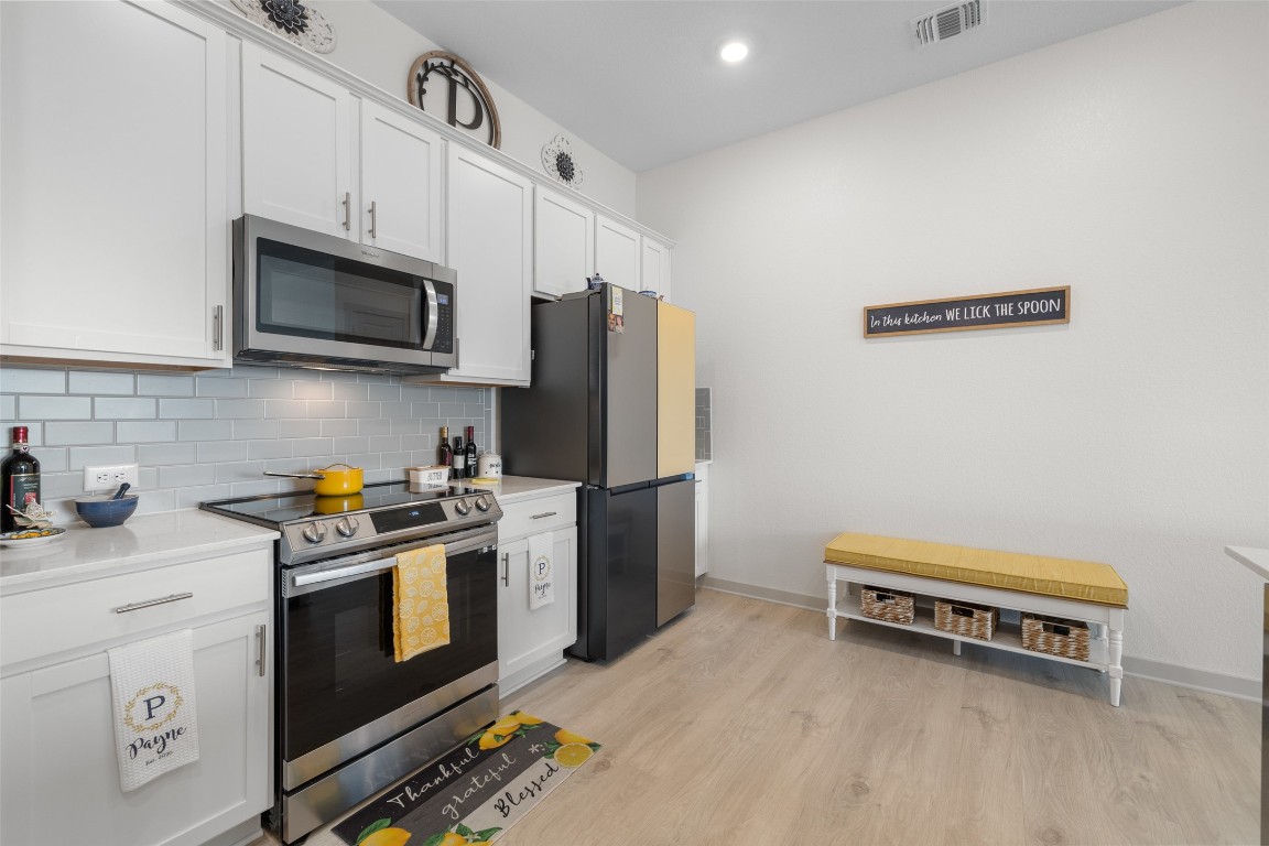 109 Rambling Rapids Drive Georgetown, TX 78628 - Photo 15 of 37 Kitchen featuring stainless steel appliances, white cabinetry, light wood-type flooring, decorative backsplash, and recessed lighting