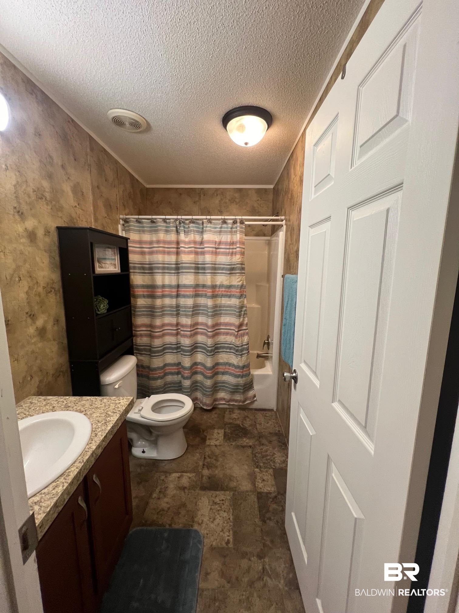 1985 Ridgewood Drive South Lillian, AL 36549 - Photo 10 of 40 Full bathroom with toilet, shower / tub combo, a textured ceiling, and vanity