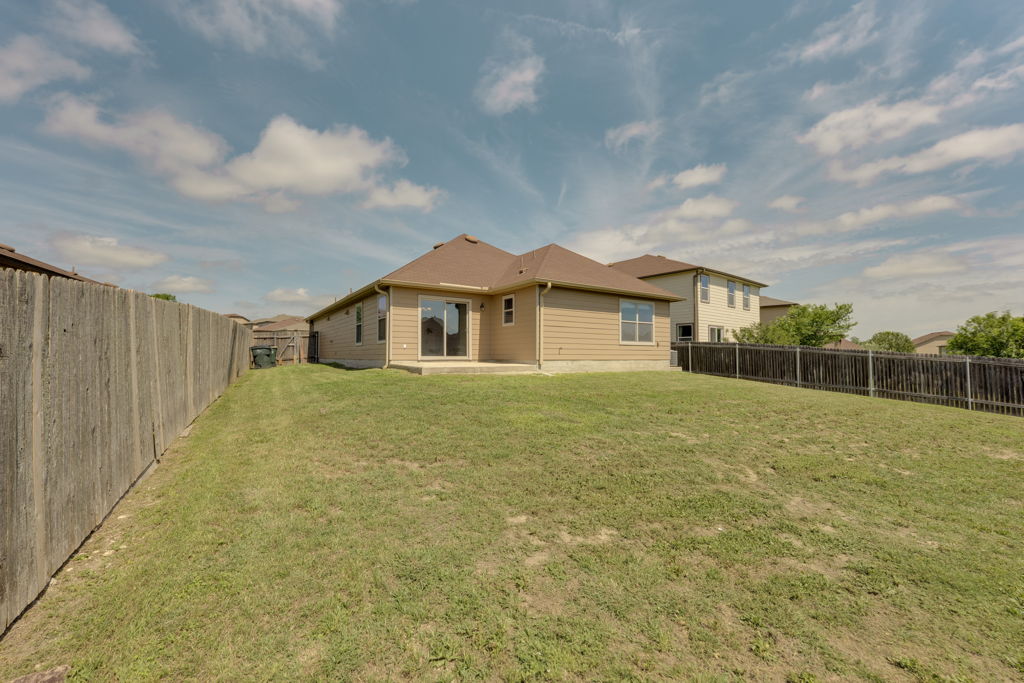 210 Cushman Drive Kyle, TX 78640 - Photo 21 of 21 Expansive backyard featuring a large grass area, a concrete patio, and a privacy fence