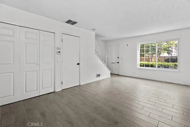 a view of an empty room with a window and wooden floor