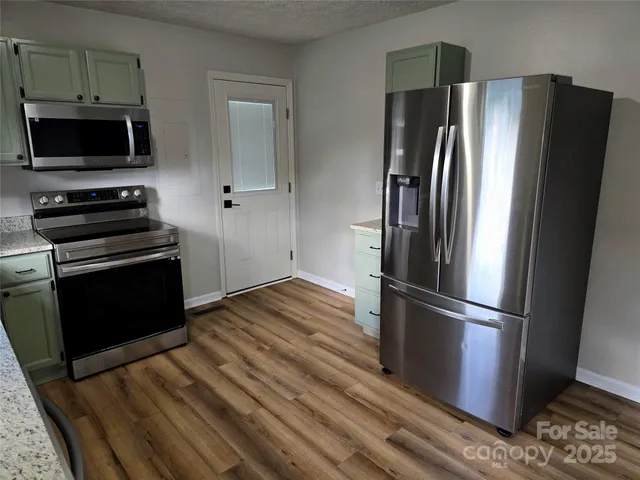 a kitchen with a refrigerator stove and wooden floor