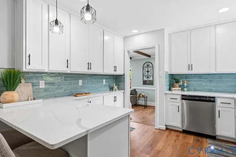 a kitchen with granite countertop a refrigerator oven a sink dishwasher and white cabinets with wooden floor