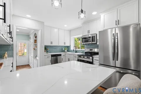 a kitchen with a sink dishwasher and white cabinets with wooden floor
