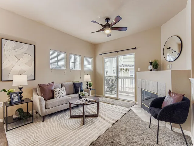 a living room with furniture a rug potted plant and a window