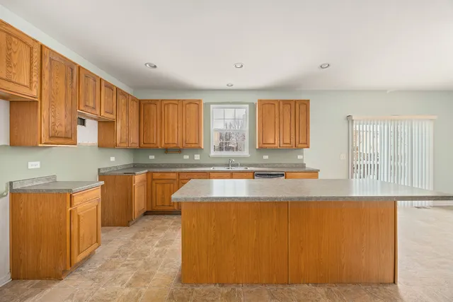 a large kitchen with granite countertop a sink window and cabinets