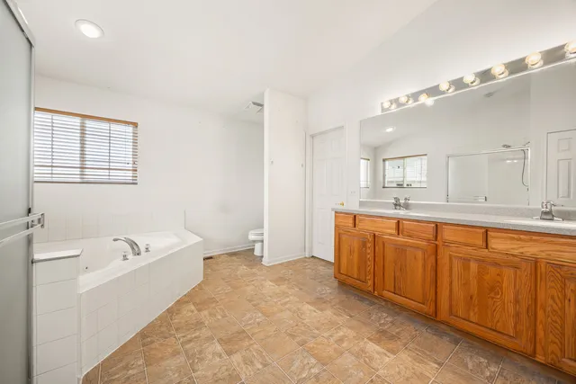a spacious bathroom with a tub sink and mirror