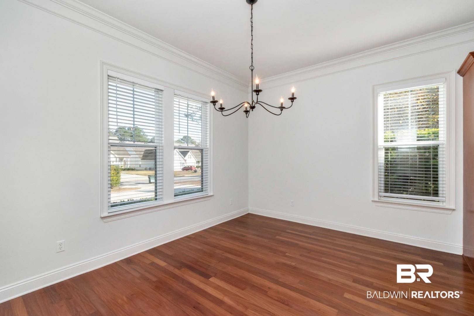 30585 Pine Court Daphne, AL 36527 - Photo 31 of 49 Empty room featuring dark wood-style floors, healthy amount of natural light, a chandelier, and ornamental molding