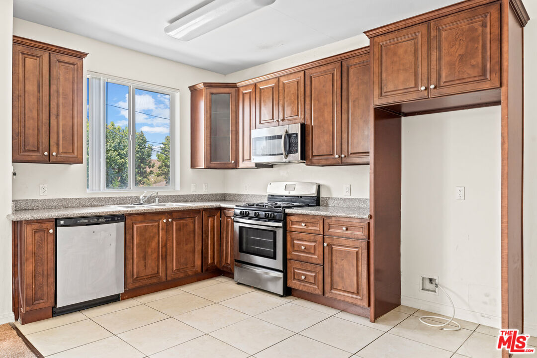 7122 Amigo Avenue Reseda, CA 91335 - Photo 5 of 16 a kitchen with stainless steel appliances granite countertop a refrigerator and wooden cabinets