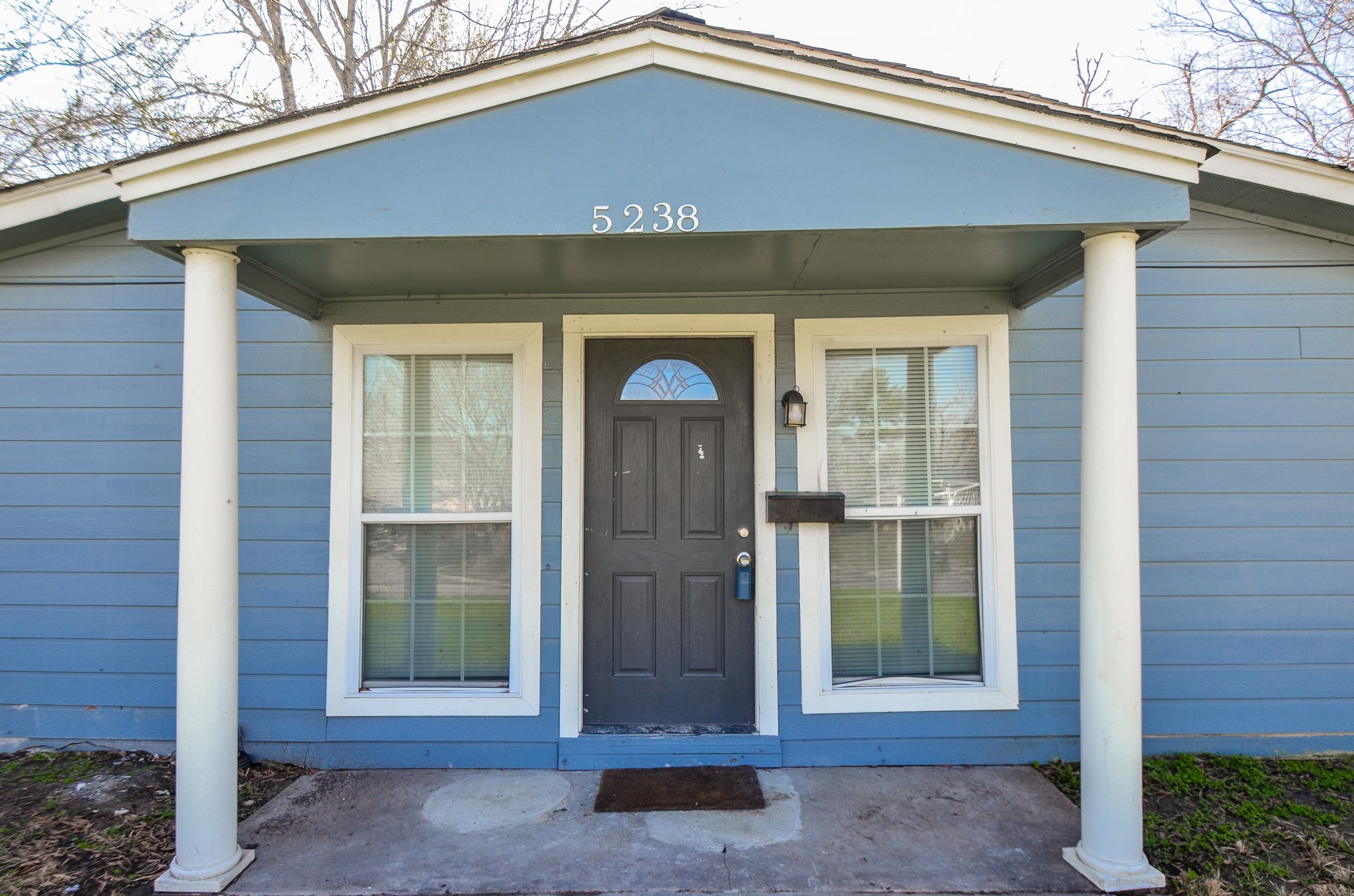 5238 Keystone Street Houston, TX 77021 - Photo 2 of 31 Charming blue house with a welcoming front porch featuring white columns and a central door, flanked by two large windows.