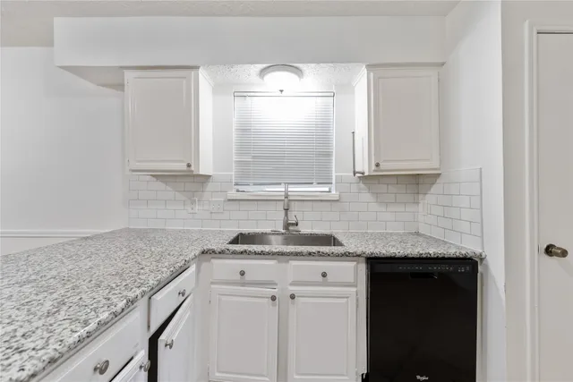 a kitchen with granite countertop white cabinets and a sink