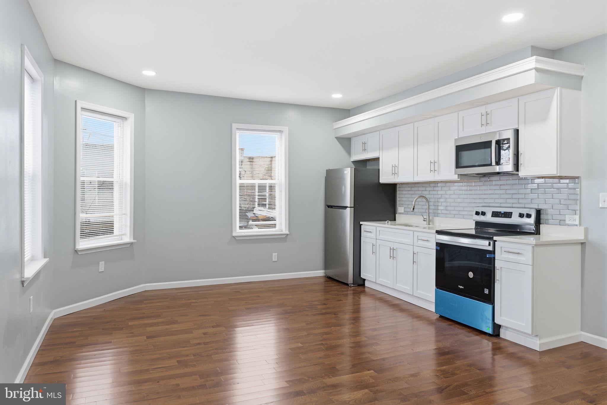 3128 F Street Philadelphia, PA 19134 - Photo 18 of 30 a kitchen with stainless steel appliances a white refrigerator a stove top oven a sink and dishwasher with wooden floor