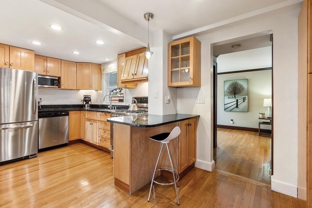 16 Conant Road Brookline, MA 02467 - Photo 13 of 31 a kitchen with granite countertop a refrigerator a stove a sink and white cabinets with wooden floor
