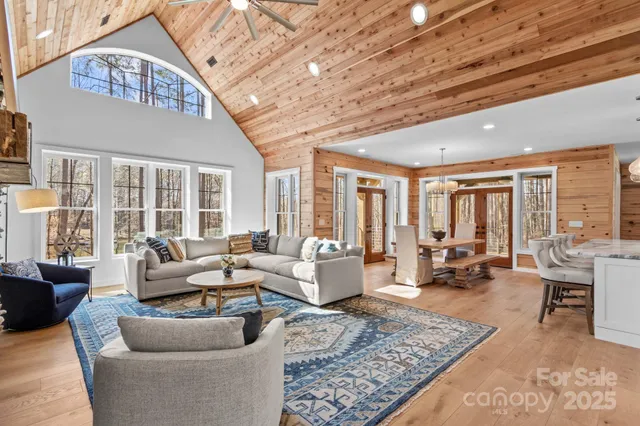 a living room with furniture large windows and wooden floor