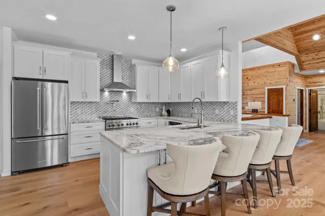 a kitchen with stainless steel appliances granite countertop a refrigerator a sink a stove a dining table and chairs