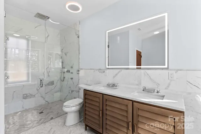 a bathroom with a double vanity sink toilet mirror and shower