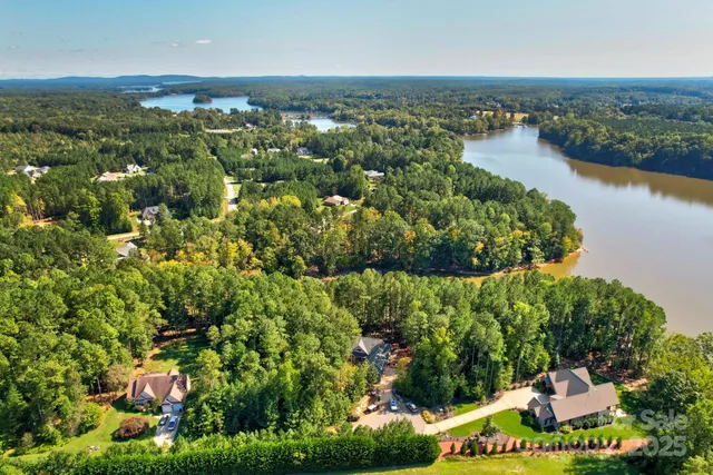 an aerial view of a residential houses with outdoor space and trees all around
