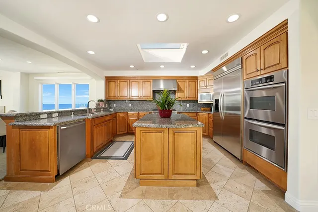 a large kitchen with stainless steel appliances kitchen island granite countertop a refrigerator and a sink