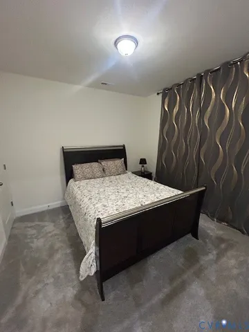 a bed sitting in a bedroom next to a curtain and a curtain