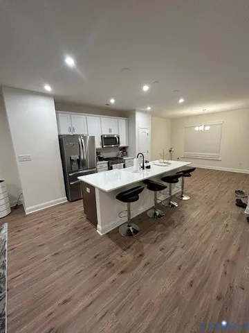 a open kitchen with a sink dishwasher a dining table chairs refrigerator and cabinets