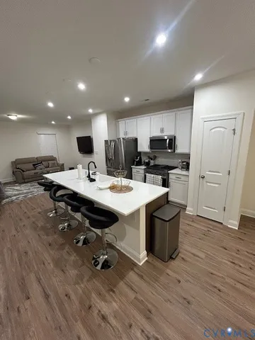 a kitchen with stainless steel appliances kitchen island granite countertop a sink dishwasher and a stove with wooden floor