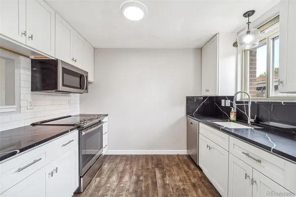 a kitchen with stainless steel appliances granite countertop a sink stove and microwave