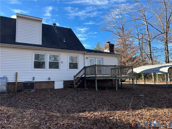 a backyard of a house with wooden deck and chairs