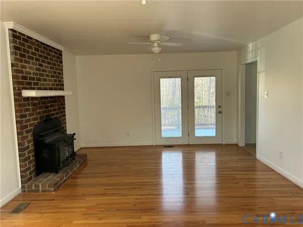 a view of an empty room with window and wooden floor
