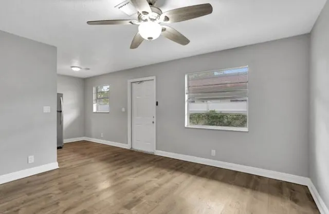 an empty room with fan and windows