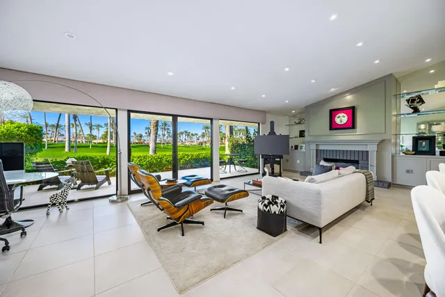 a living room with furniture fireplace and floor to ceiling windows